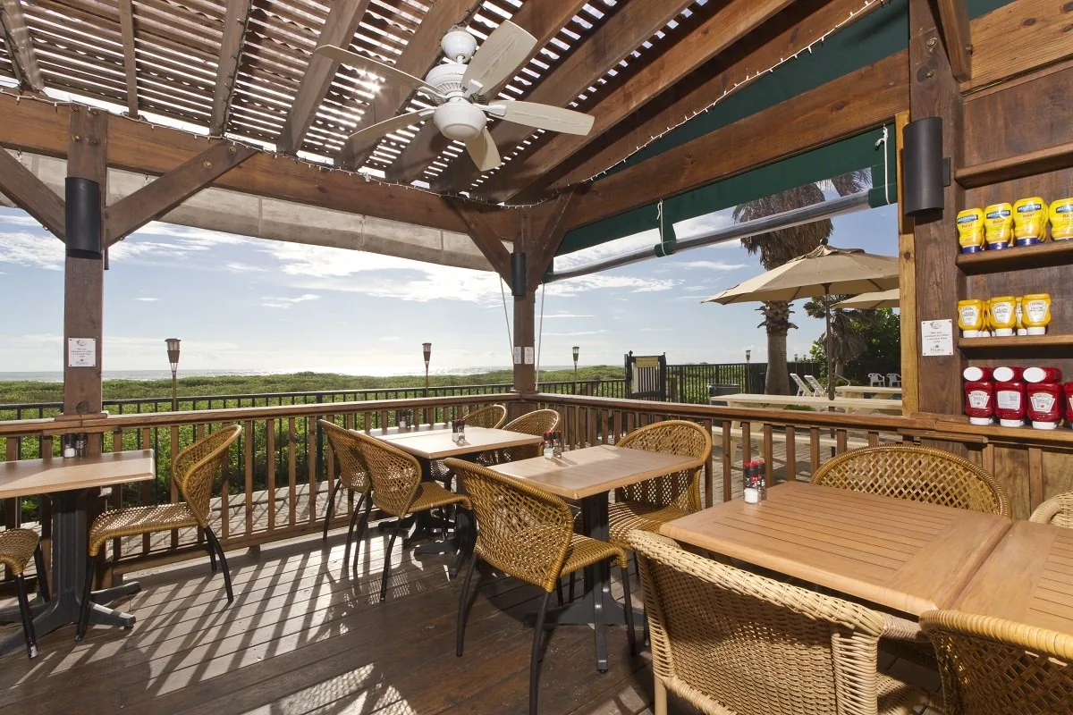 The covered wooden deck with wicker chairs, ceiling fans and a view over the dunes to the Gulf