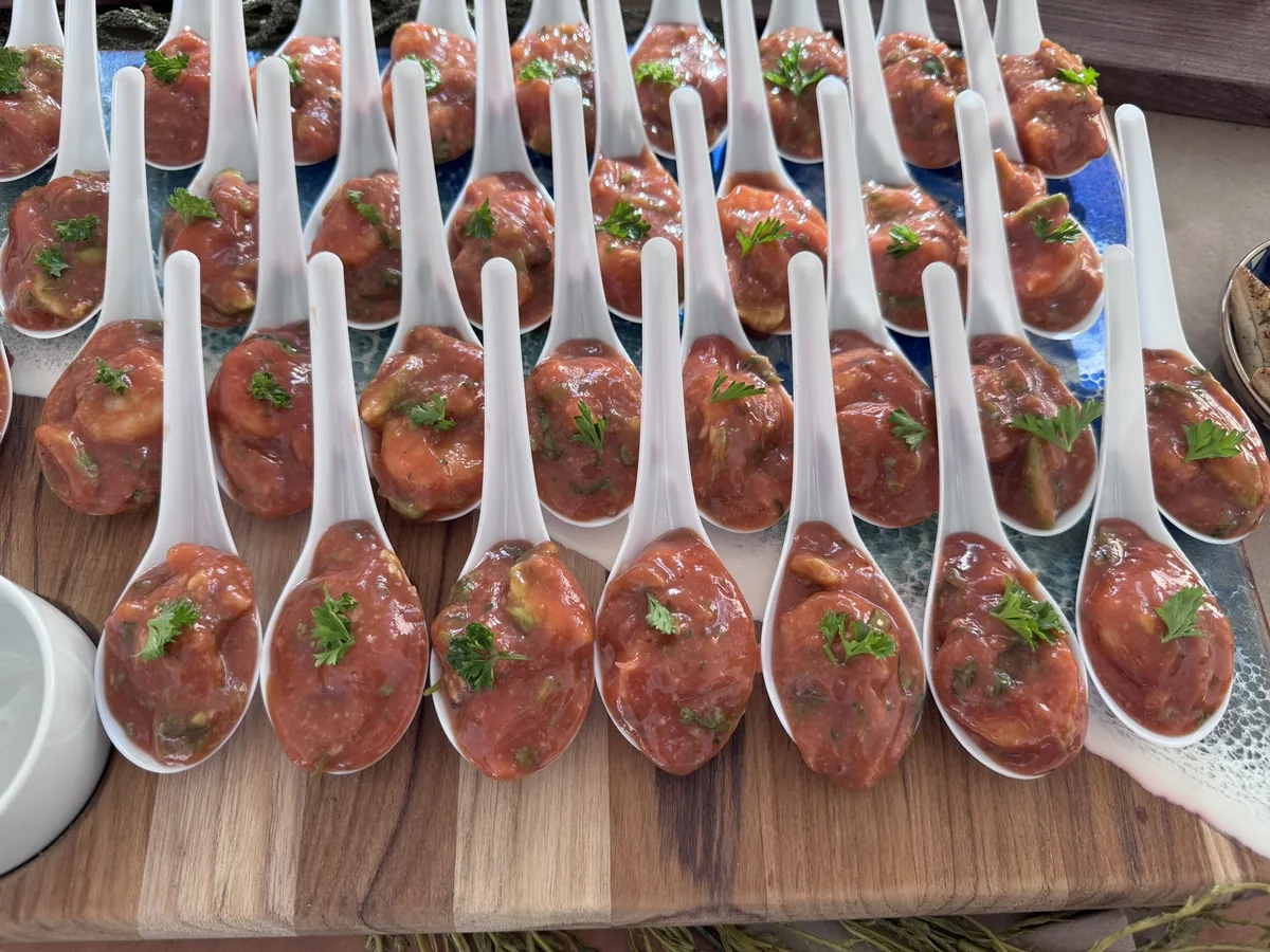 Rows of appetizer spoons filled with shrimp cocktail and topped with parsley