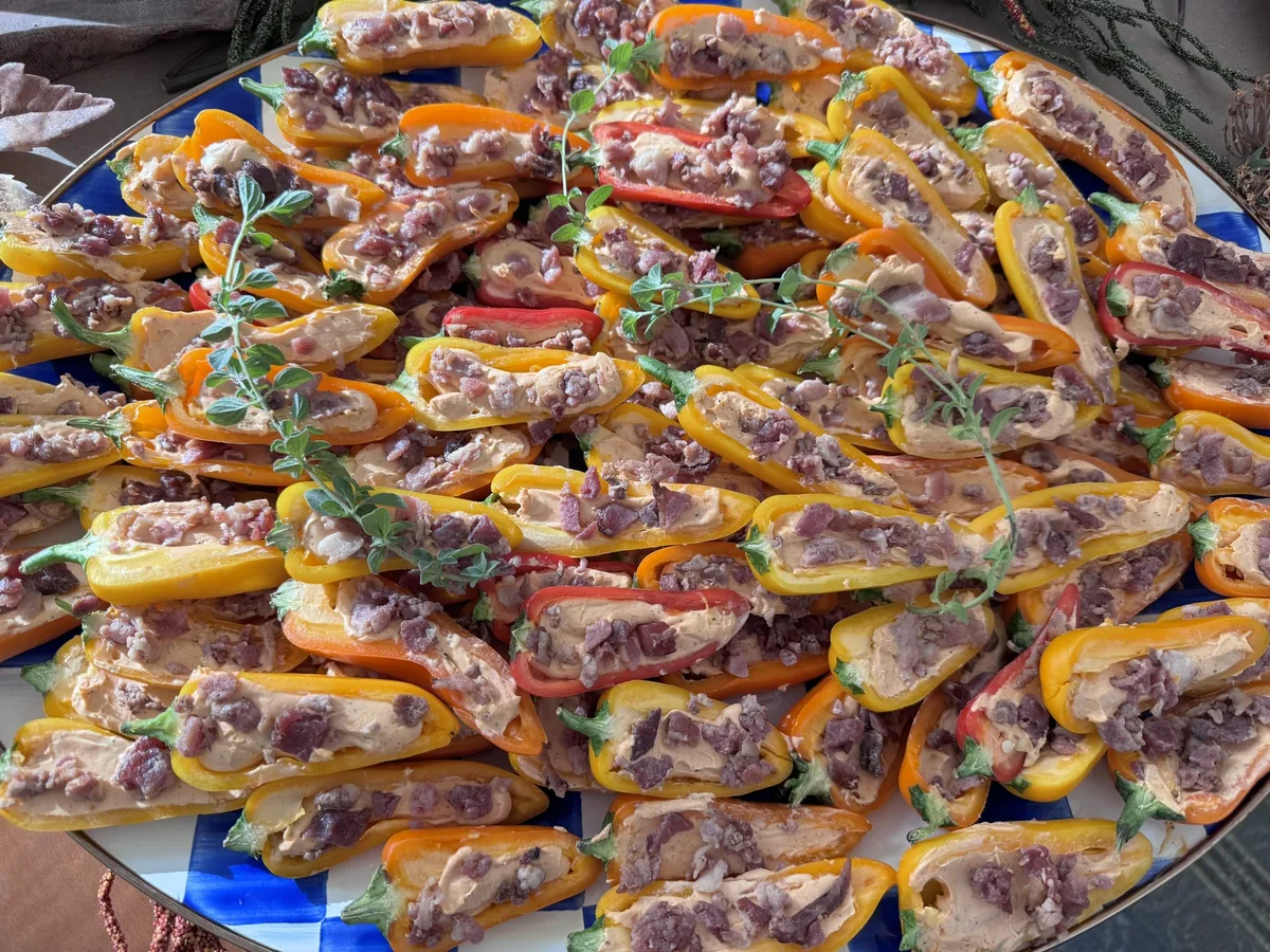 A platter of stuffed mini sweet peppers garnished with fresh herbs