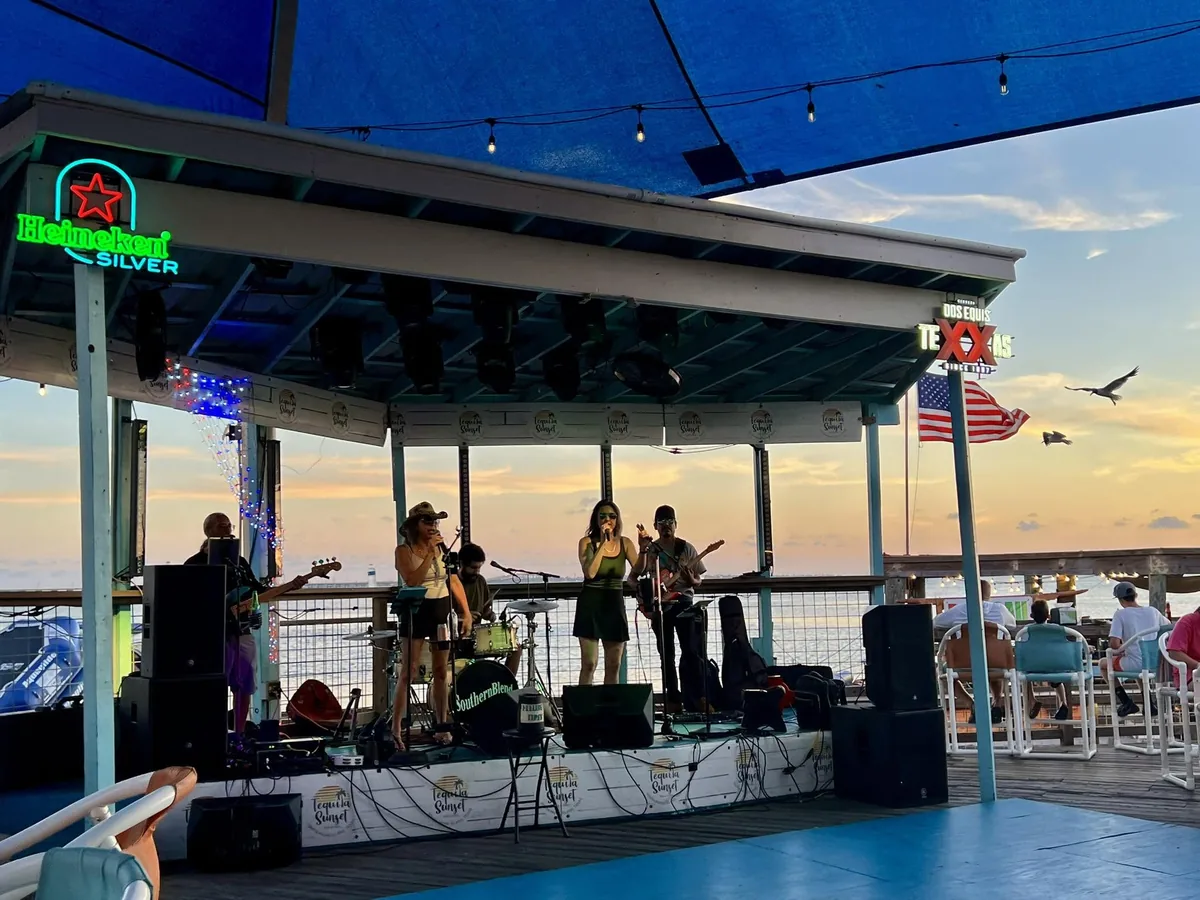 A band playing on the covered stage at dusk, with the bay behind