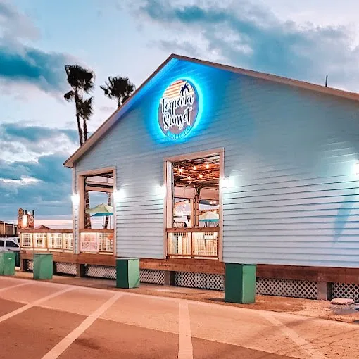 The blue Tequila Sunset building with its lit round sign at dusk