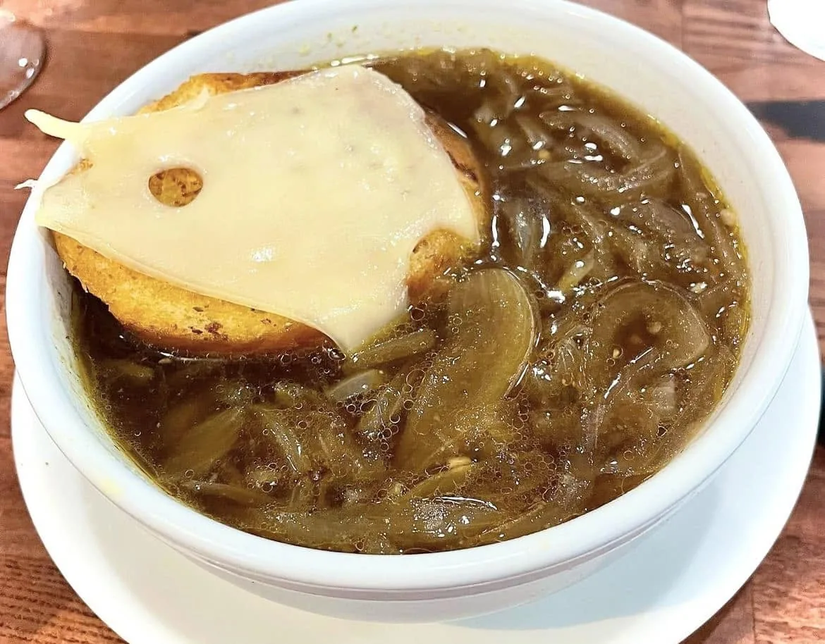 A bowl of French onion soup topped with toast and melted Swiss cheese